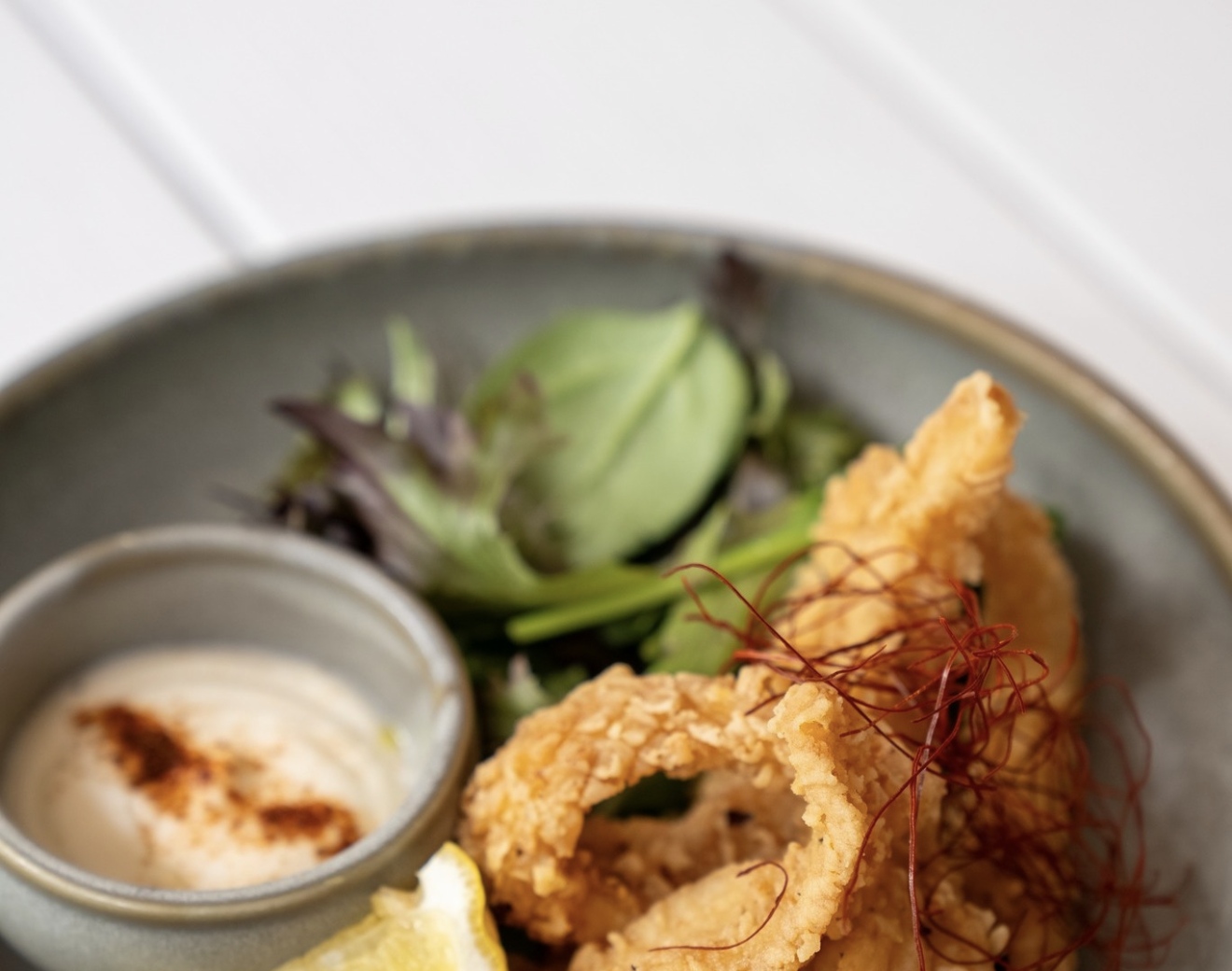 Poppies signature handmade calamari — golden, crispy, served with garlic aioli at River Quay South Bank